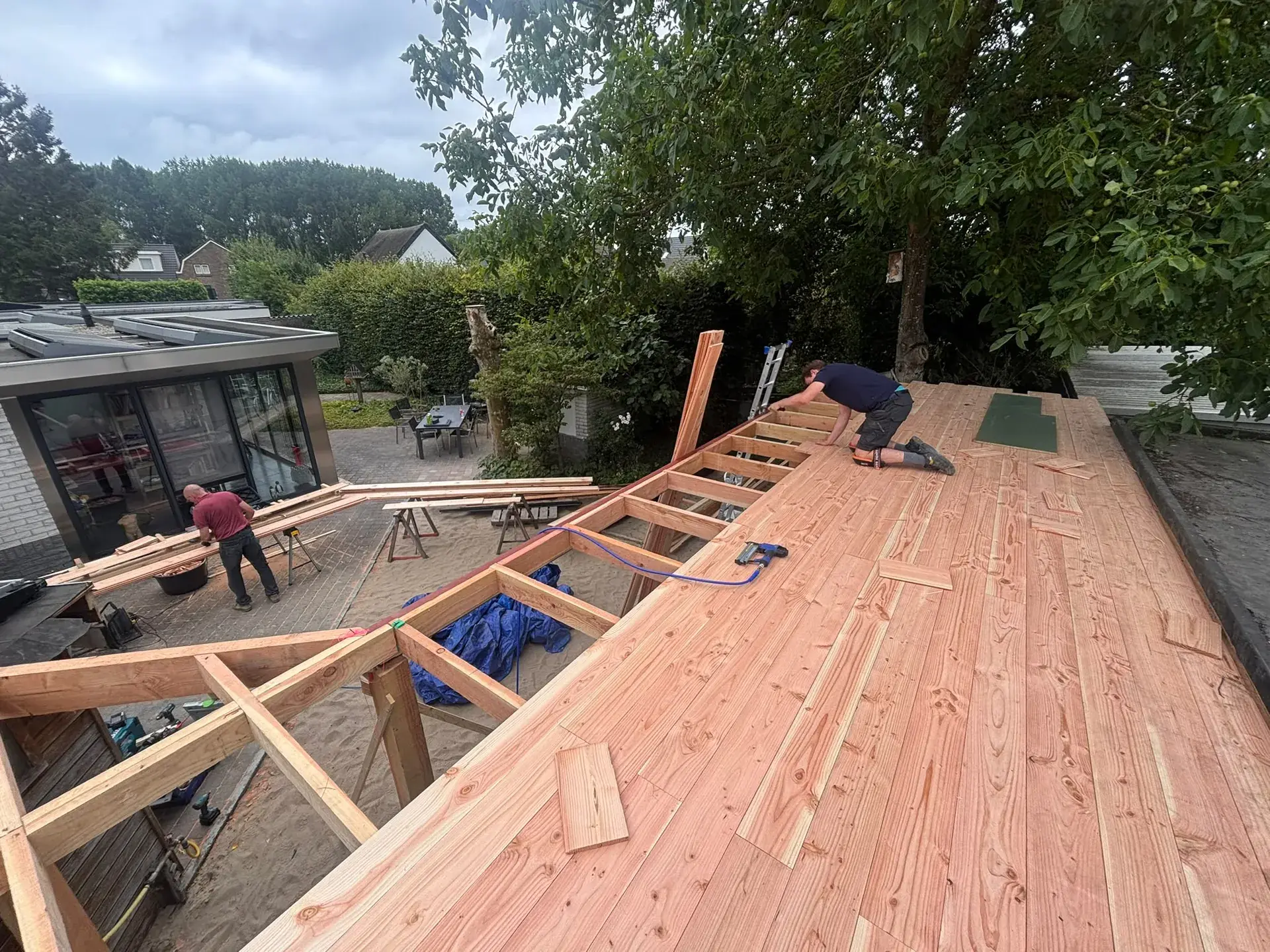 Vakman legt douglas dakbeschot op de balklaag van de carport