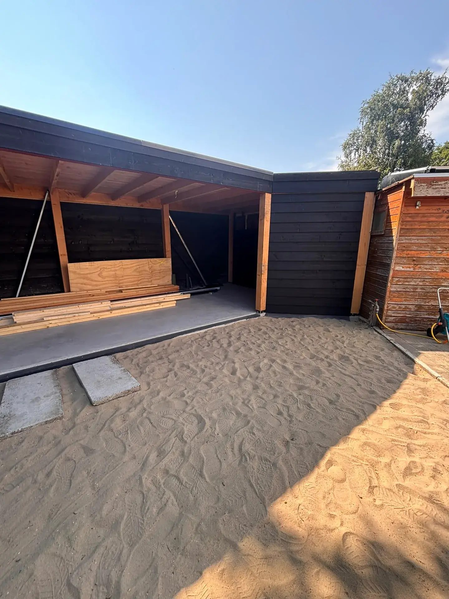 Carport bijna klaar, met zwarte houten gevelbekleding, douglas staanders en houten plafond