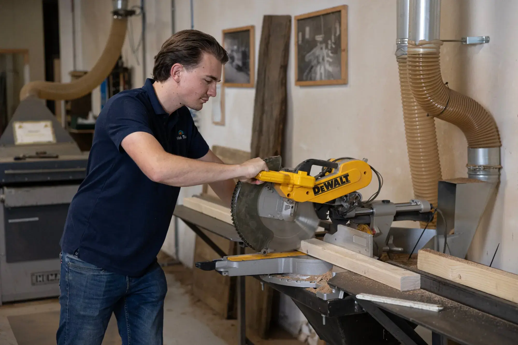 Een van de oprichters kort een balk af op de afkortzaag in de werkplaats